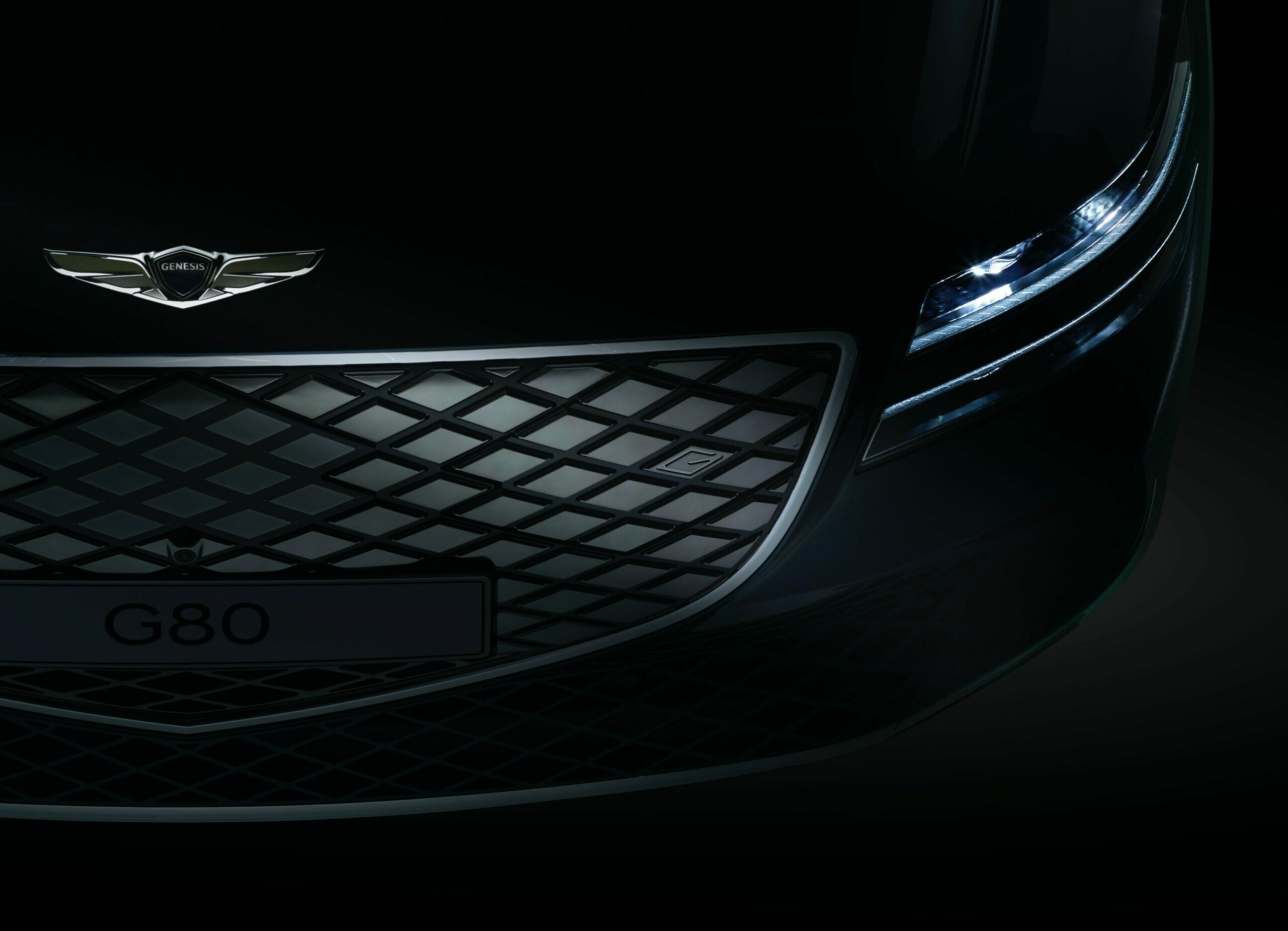 Front of black Genesis G80 in the dark