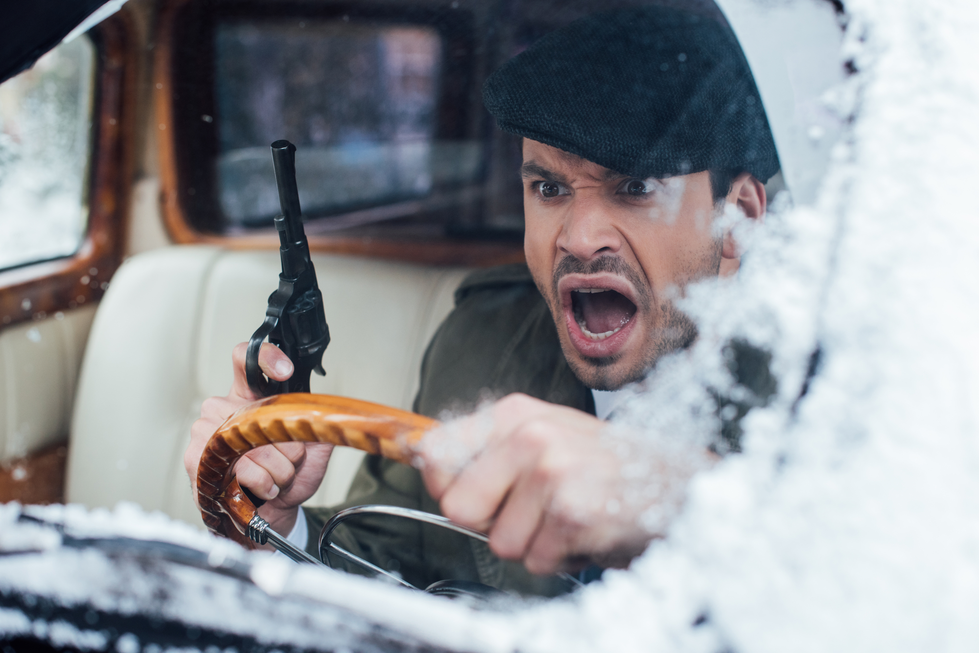 Angry man with a pistol inside old car