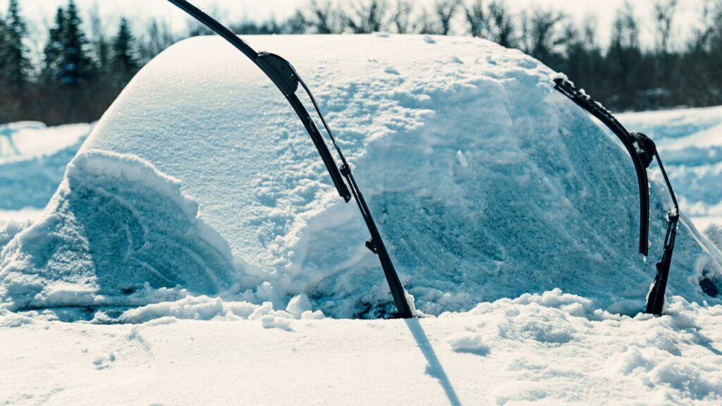 Car's windshield is totally covered with snow and ice, windshield wipers are lifted up